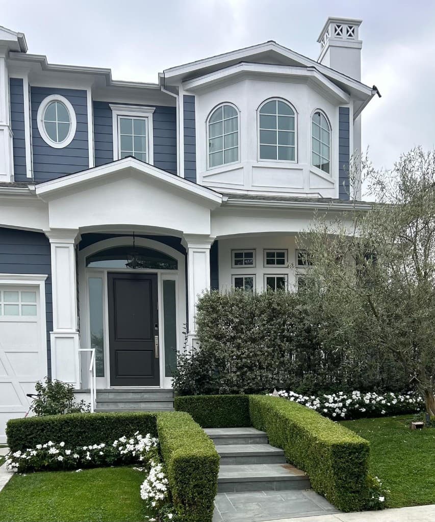 Blue and white luxury home with sculpted landscaping